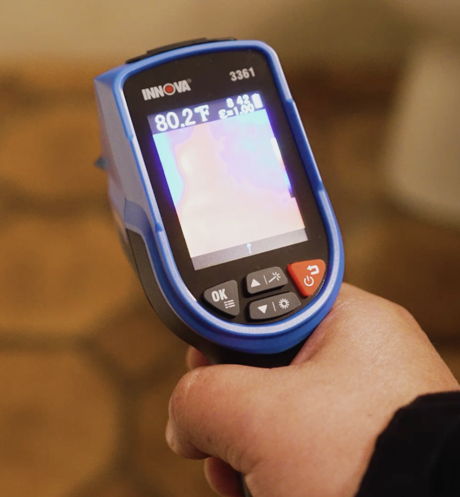 Technician using a thermal camera to detect a slab leak under a home floor