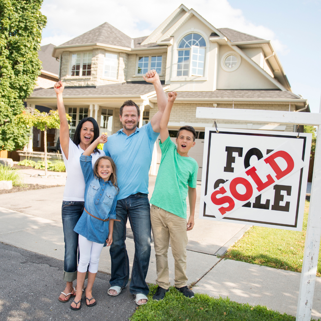 Happy Home Sellers Happy family celebrating after selling their home with a sold sign in front of the house