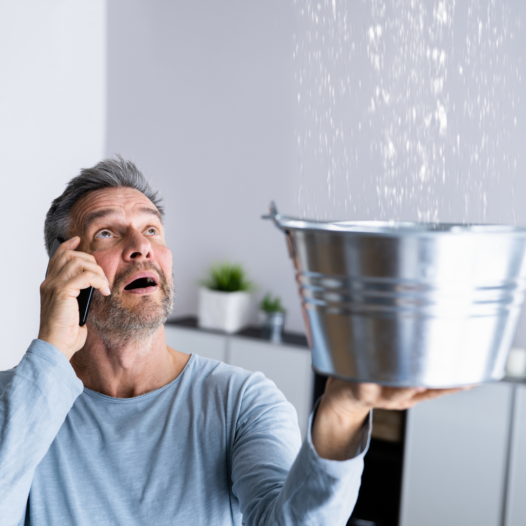 Homeowner calling repipe specialist while catching water leak from ceiling in Orange County home